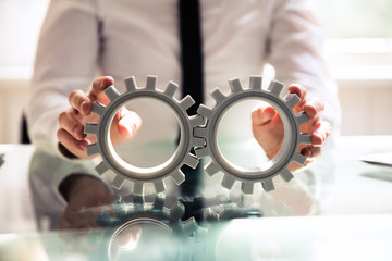 Close-up Of A Person Connecting Two Gears