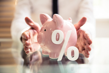 Person Protecting Piggybank With Percentage Symbol