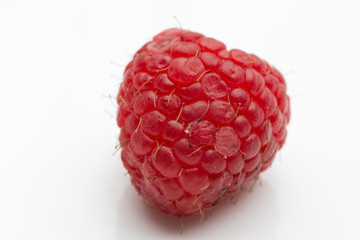 Closeup of a raspberry in a spoon on a white background