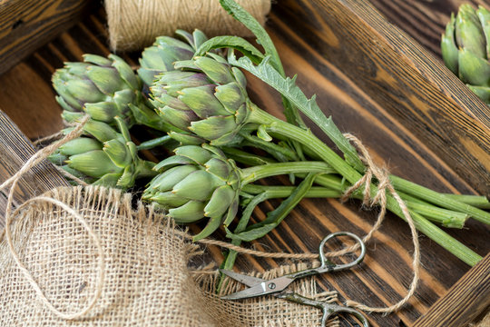 Supplies and materials for artichoke bouquet on wooden background. Top view.