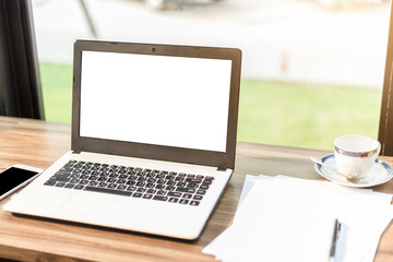 Fototapeta premium Mockup image of laptop with blank white screen,smartphone,coffee cup on wooden table of In the coffee shop.