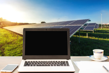 Mockup image of laptop with blank white screen,smartphone,coffee cup on wooden table of solar panel on blue sky background, Alternative energy concept,Clean energy,Green energy.