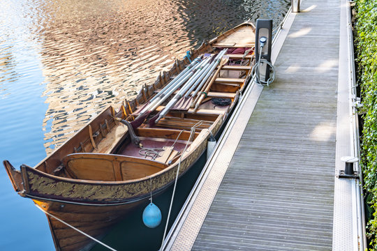 Large Row boat with Oars docked in the Water with a Reflection