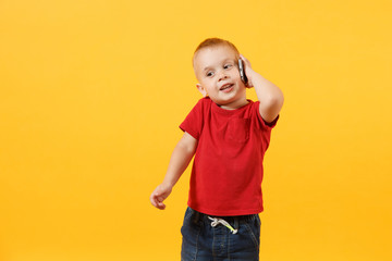 Little kid boy 3-4 years old in red t-shirt talking on mobile phone, conducting pleasant...