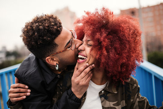Young man biting on cheek of his girlfriend