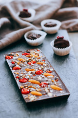 Raw homemade chocolate with nuts, cranberris on black background