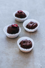 Healthy raw energy chocolate candy with cocoa, coconut, sesame, chia, cranberries and icing. Vegan chocolate truffles on a gray background. Copy space.