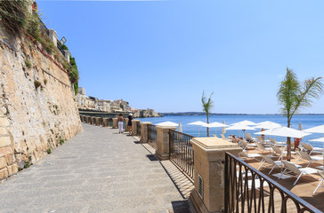 Fragment of Ionian sea coast with promenade and beach in Syracuse in Sicily.