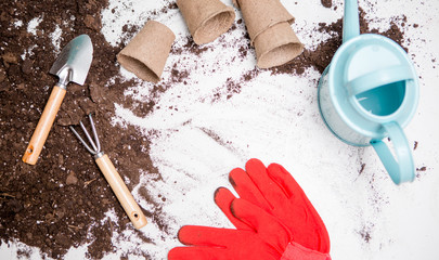Photo of top soil for transplanting plants, rake, scoop, watering can, red gloves
