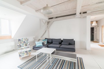 Bright attic living room with wooden ceiling beams.