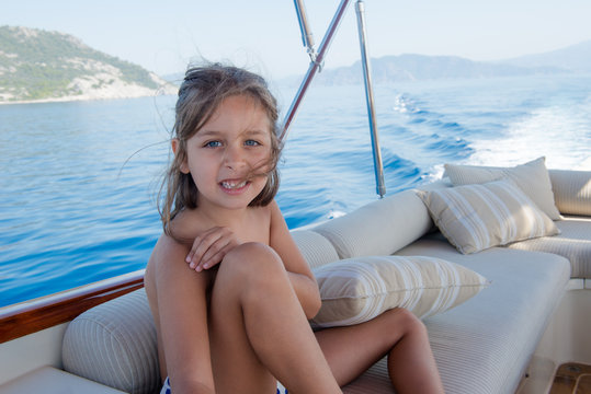 cute girl is smiling and sitting on boat