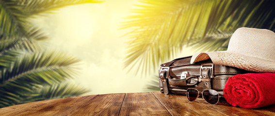 Summer suitcase of brown color and background of exotic palms 