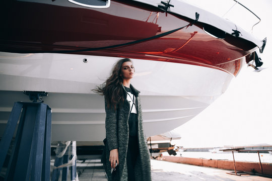 Girl posing near the yacht.Beautiful brunette posing.Girl with an earring up her nose.Summer evening the girl and the boat.