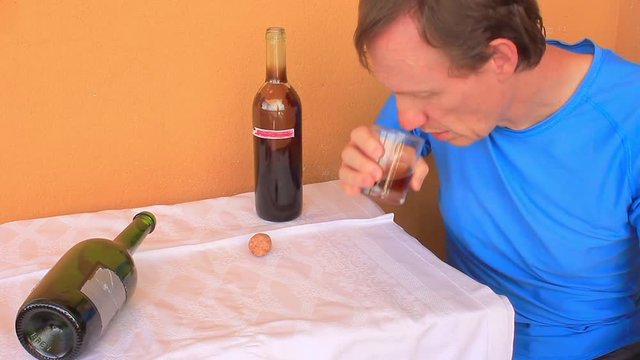 a   drunk man   shumped on   the table/ a man  swept  two  bottles  of wine