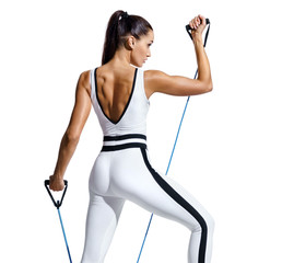 Sporty woman performs exercising with resistance band. Photo of fitness model in fashionable...