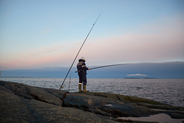 the fisherman stands on a rocky shore