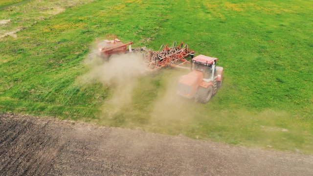 Aerial shot of a farmer in tractor seeding. Sowing agricultural crops at field.