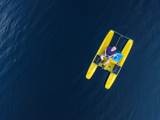 Aerial view of a man who swims on a lake on a pedal catamaran, a water bike