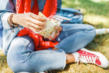 Young woman eating sandwich and having lunch break outdoors in park