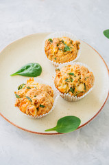 Savory potato spinach and feta muffins served on a plate. White stone background.