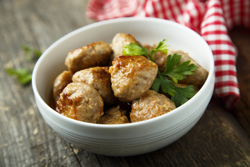 Homemade meatballs with fresh parsley in a white bowl