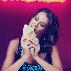 Sexy woman sitting at table in night club or bar and eating kebab or shaverma. Fashion style portrait