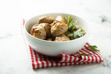 Homemade meatballs with fresh parsley in a white bowl