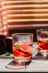 Refreshing blood orange water or infused water in a glass on a wooden background.