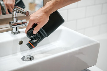 Removal of blockage in the sink, the hand of a man with a bottle of a special remedy with granules....