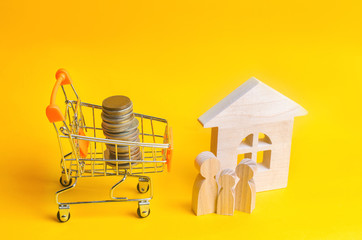 family is standing near the house. wooden little men. Coins in a shopping basket. Concept of real...