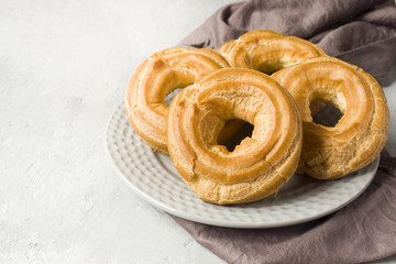 Custard cake rings on a plate on a grey textured background. Selective focus. Copy space
