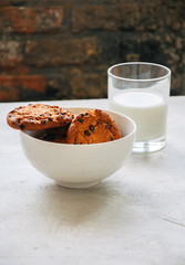 American chocolate chip cookies with glass of milk on a white stone background. Top view and copy space.