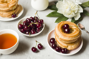 Custard cakes ring with cherry on a plate on a gray textured background. Selective focus. Copy space