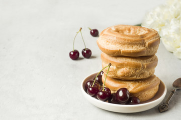 Custard cakes ring with cherry on a plate on a gray textured background. Selective focus. Copy space