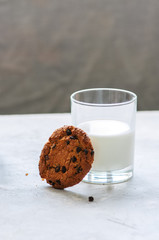 American chocolate chip cookies with glass of milk on a white stone background. Top view and copy space.