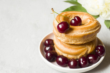 Custard cakes ring with cherry on a plate on a gray textured background. Selective focus. Copy space