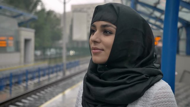 Young dreaming muslim woman in hijab is waiting for train, religion concept, urban concept