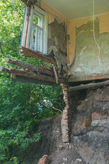 Ruined damaged building. Affected as a result of a natural disaster. A collapsed floor in the room of a private house, fragment of the wall and window. Destruction of the foundation by groundwater
