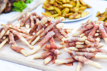 Tasty bread sticks with ham on table