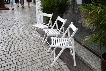 Fototapeta na wymiar three white chairs on the street