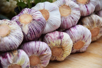 garlic braid next to a wooden box of green herbs and vegetables