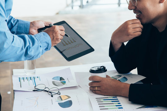 Asian businessmen convened for a meeting with  digital graphs and charts describing their work.