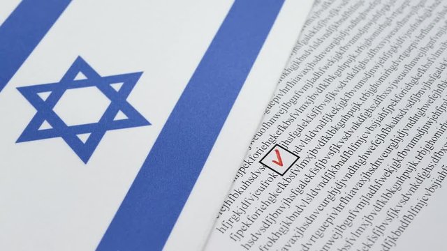 Hand voting in paper ballot by red pencil in Israel wirh Israeli flag