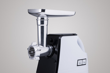 household electric meat grinder with nozzle on light grey background, close-up. kitchen appliances