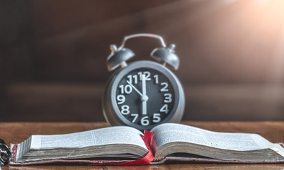 Holy bible and alarm clock on wood table. read the word of God.