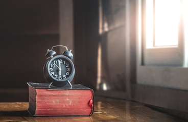 Clock on red holy Bible on wood,How much the time of man given to God,christian concept.