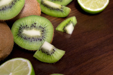 Sliced kiwi with lime on a dark brown wooden table