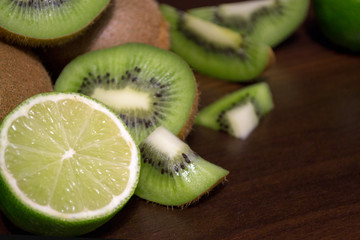 Sliced kiwi with lime on a dark brown wooden table
