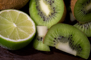 Naklejka na ściany i meble Sliced kiwi with lime on a dark brown wooden table