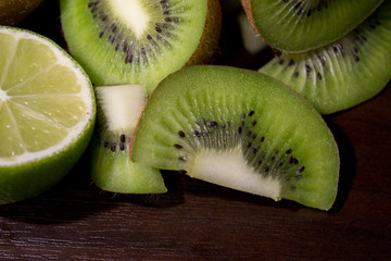 Sliced kiwi with lime on a dark brown wooden table
